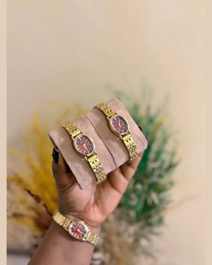 Original marketplace photo of a gold bracelet watch with a burgundy face